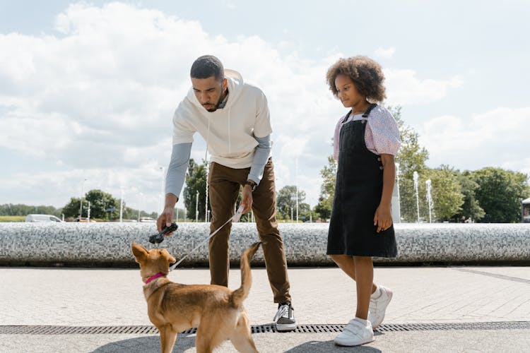 Man And Girl Walking A Dog