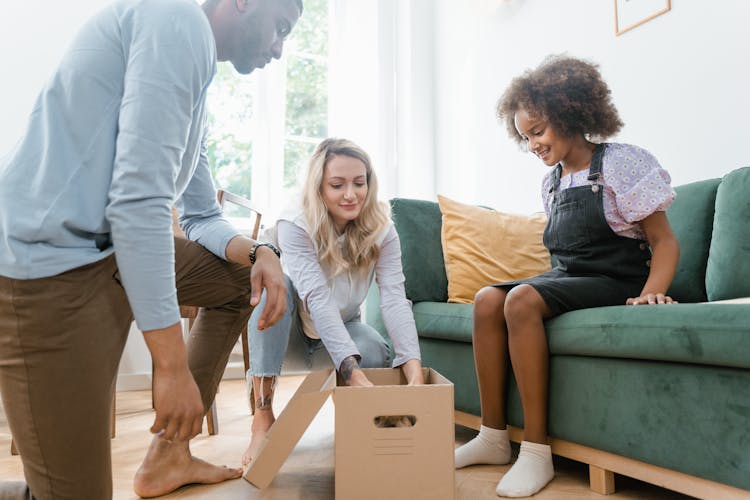 A Family In A Living Room Looking At A Box