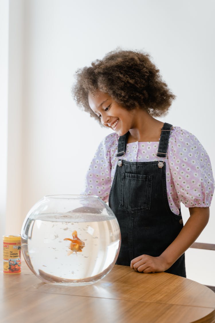 Girl Standing Beside A Fish Bowl