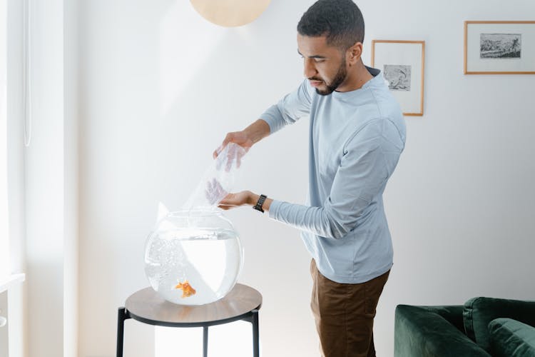 A Man Putting A Goldfish In A Fishbowl