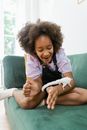 A Young Girl Sitting on the Couch while Playing with Her Pet