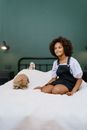 A Young Girl Sitting on the Bed with Her Pet