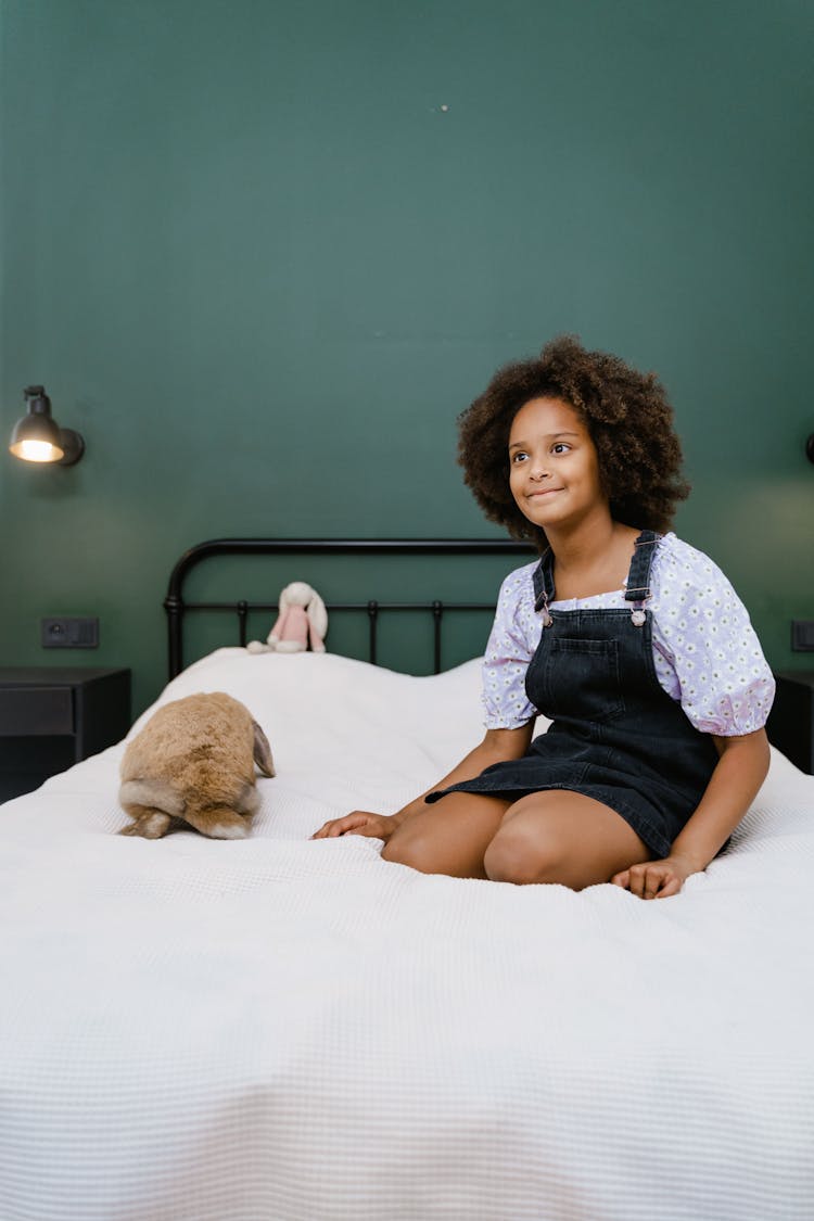 A Young Girl Sitting On The Bed With Her Pet