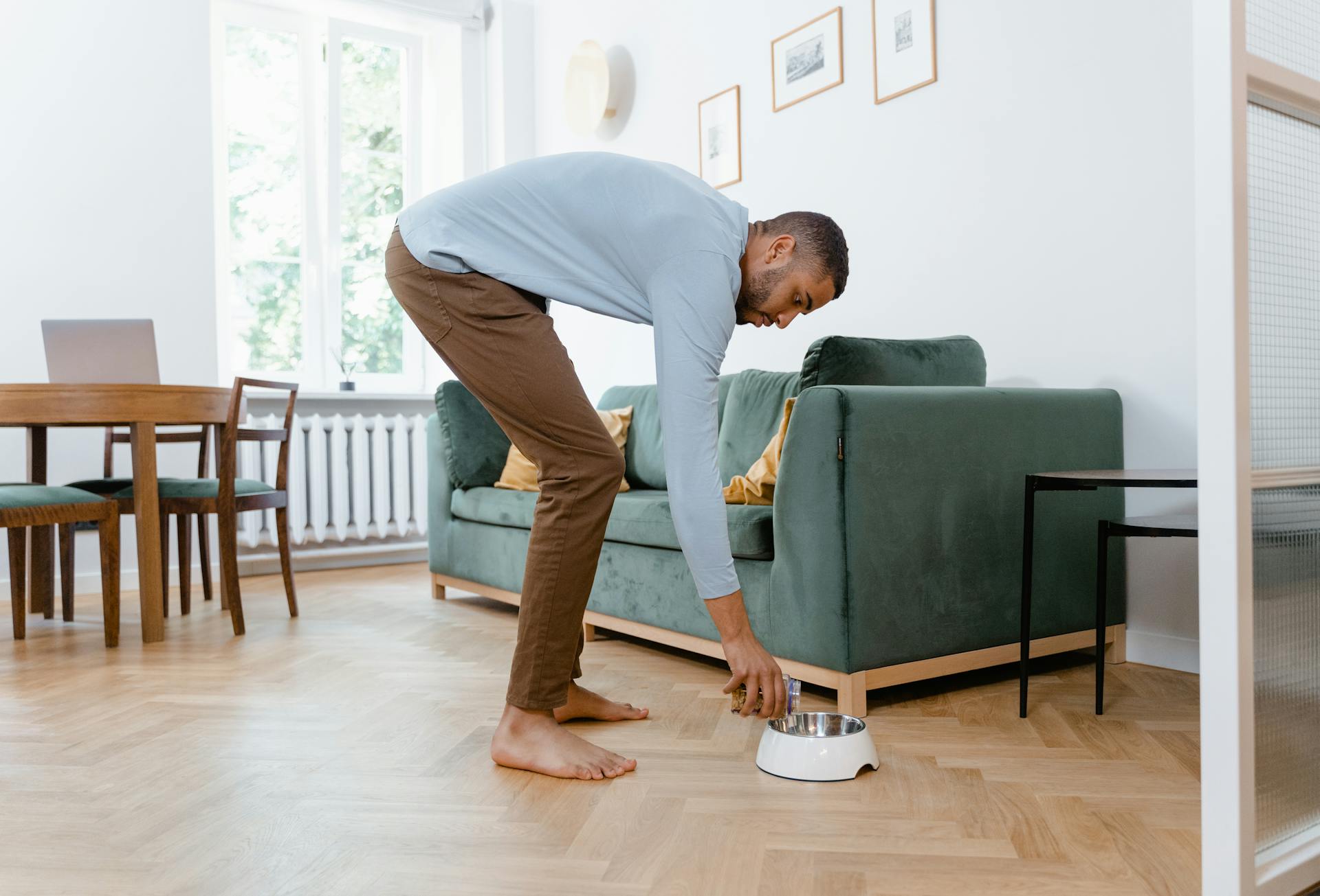 Man in Long Sleeves and Brown Pants Putting Dog Treats on Bowl