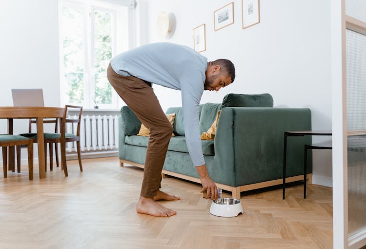 Man In Long Sleeves And Brown Pants Putting Dog Treats On Bowl 