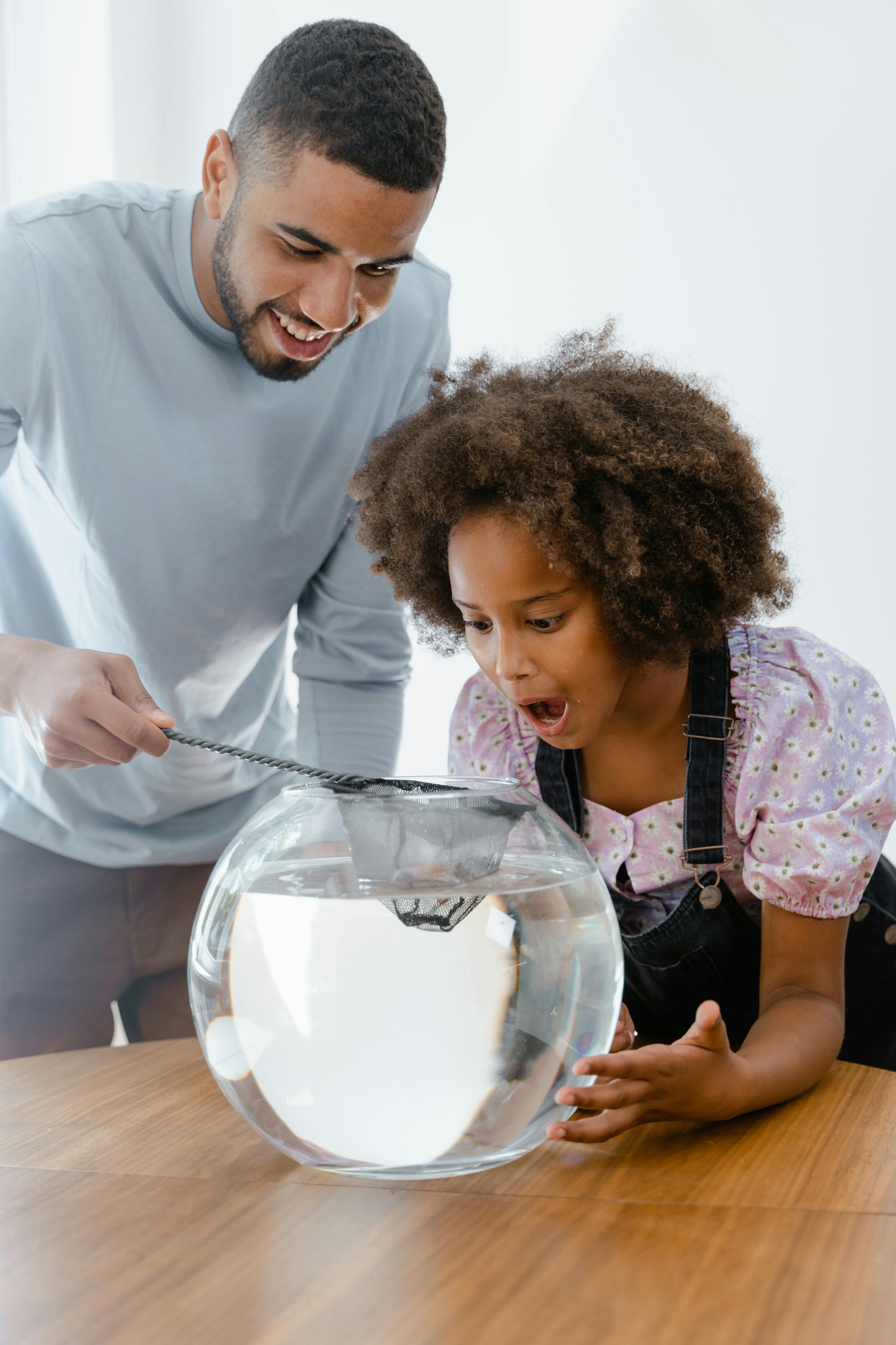 father and daughter looking at a fish bowl