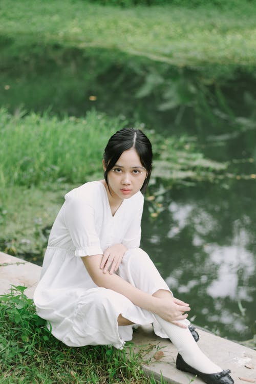 Free Woman in White Dress Sitting Near a River Stock Photo