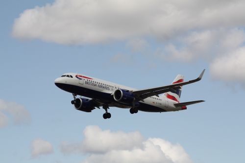 Free British Airways airplane flying amidst fluffy clouds in a bright blue sky. Stock Photo