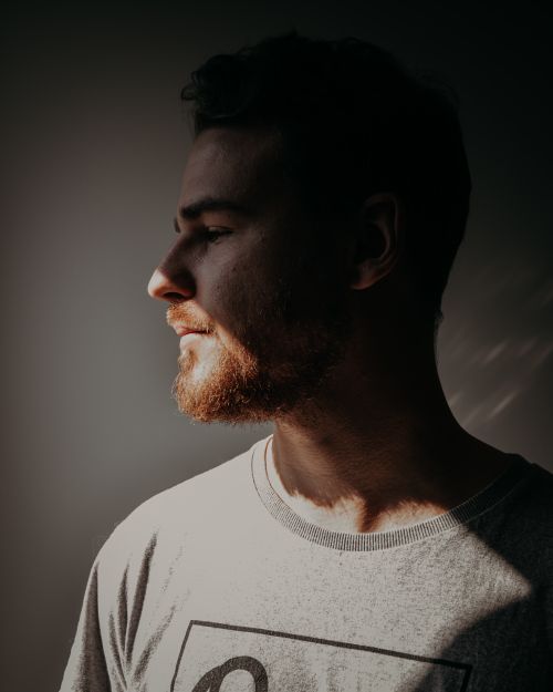 Free Artistic side portrait of a bearded man in soft lighting with shadow play. Stock Photo