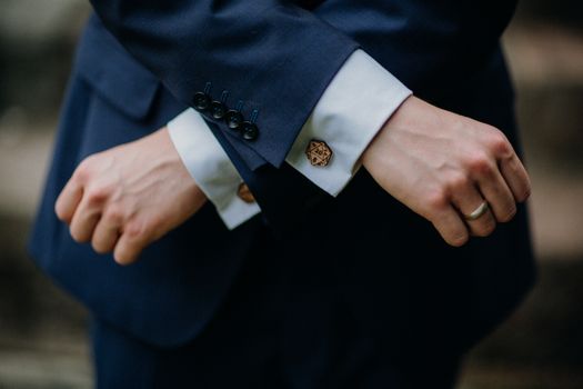Close-up of hands in a blue suit with stylish cufflinks and a ring.