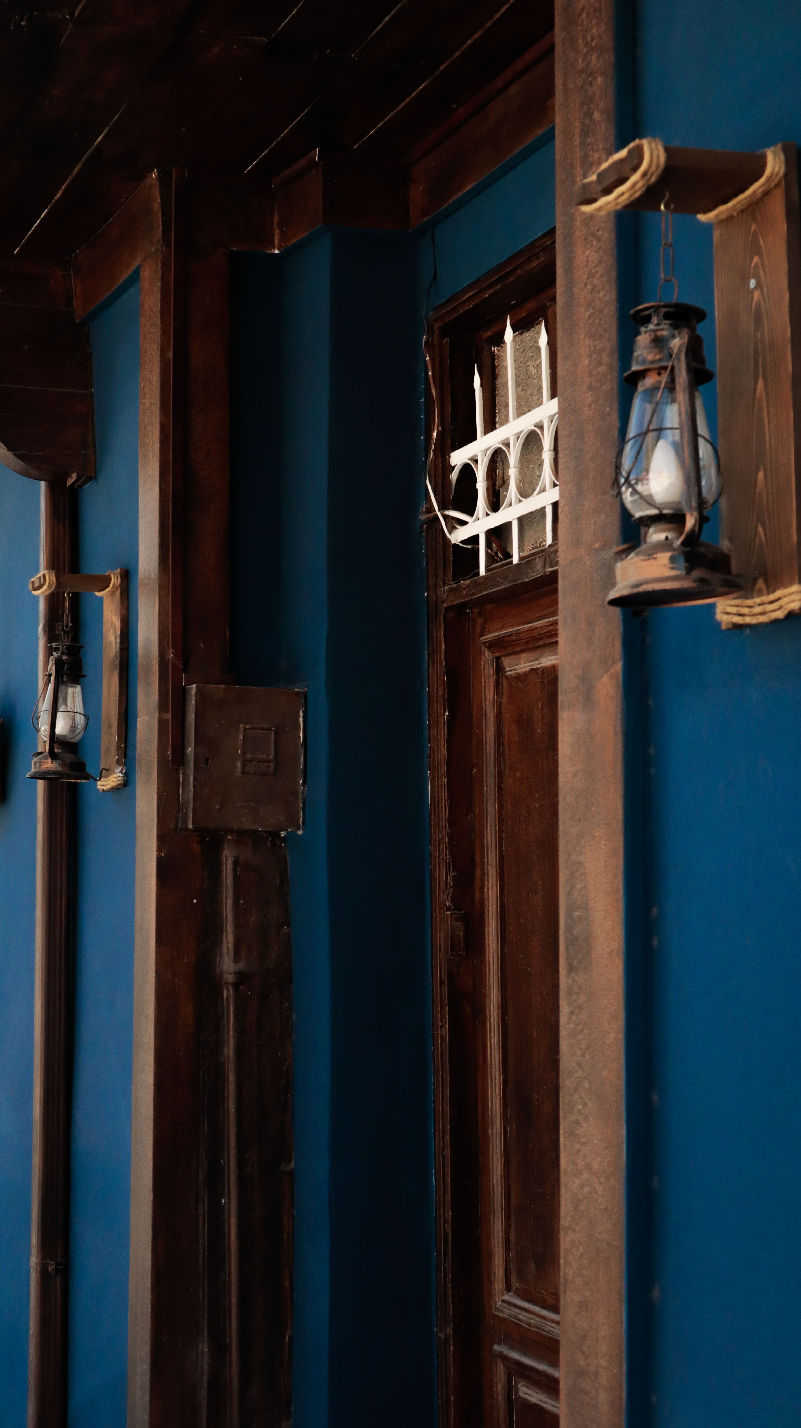 A classic entrance with wooden door and retro lantern on vivid blue walls. Perfect for vintage design themes.
