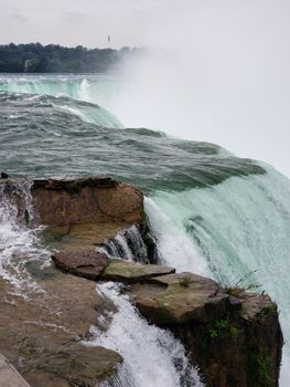 Powerful cascading water over rocks at Niagara Falls in a misty display.