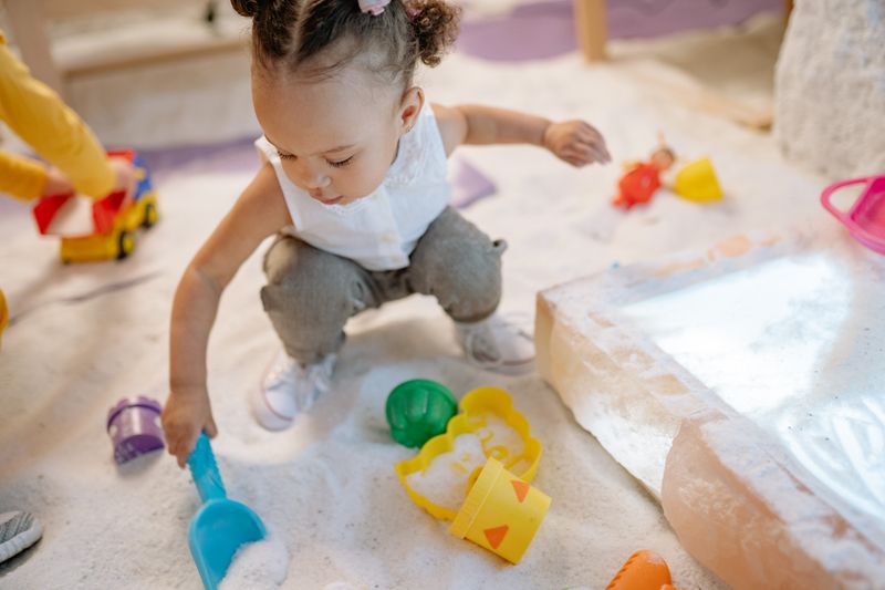 A toddler playing with colourful sand toys