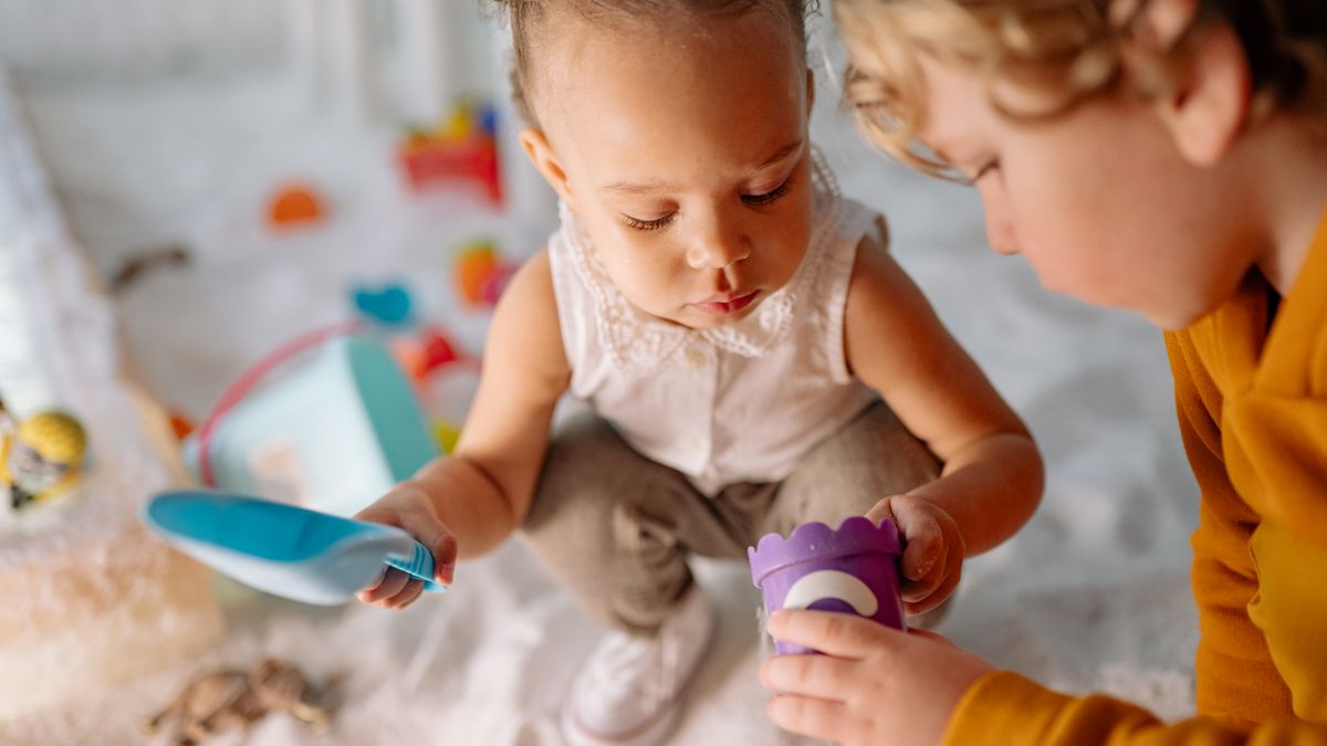 Two children playing with toys in a sandbox, enjoying a fun and creative moment.