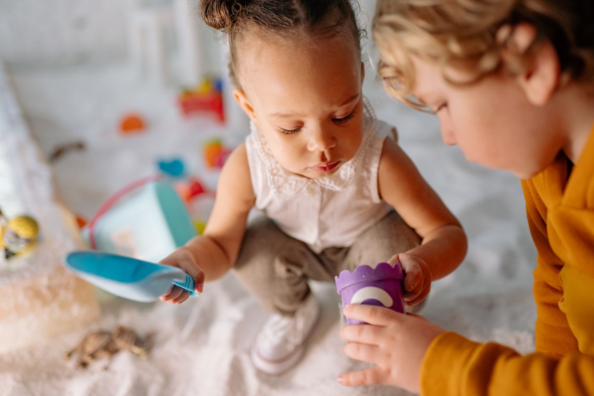 Two toddlers playing with sand toys