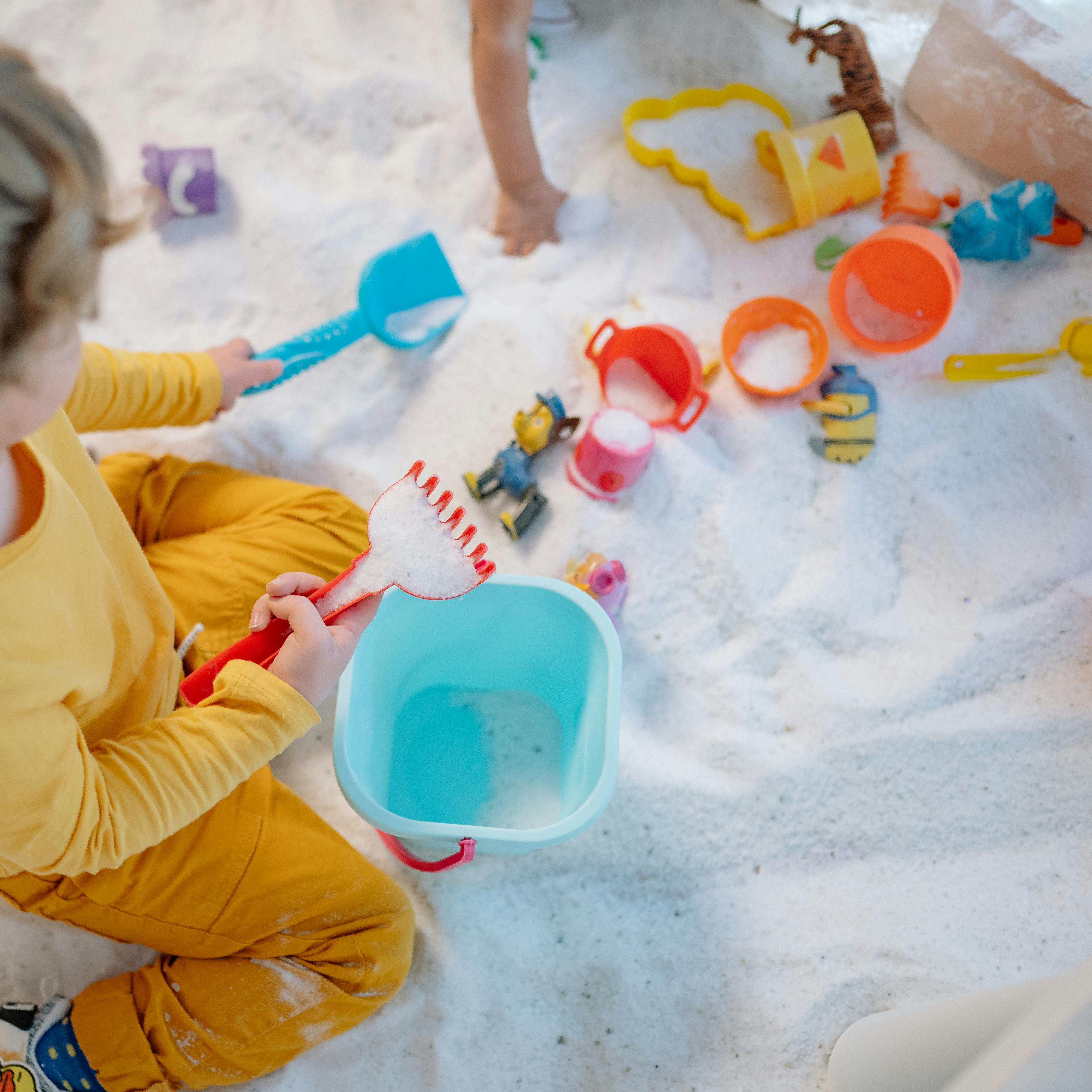 Child in Yellow Shirt Playing on Sand
