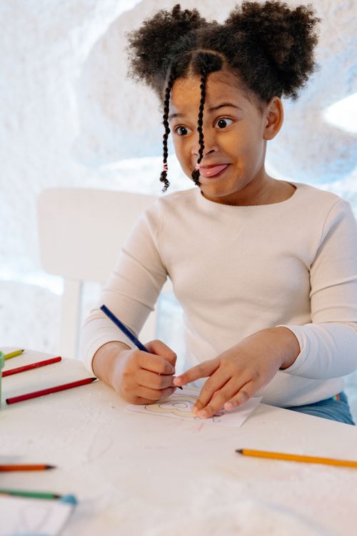 Free Young girl playfully drawing with colored pencils, expressing creativity. Stock Photo