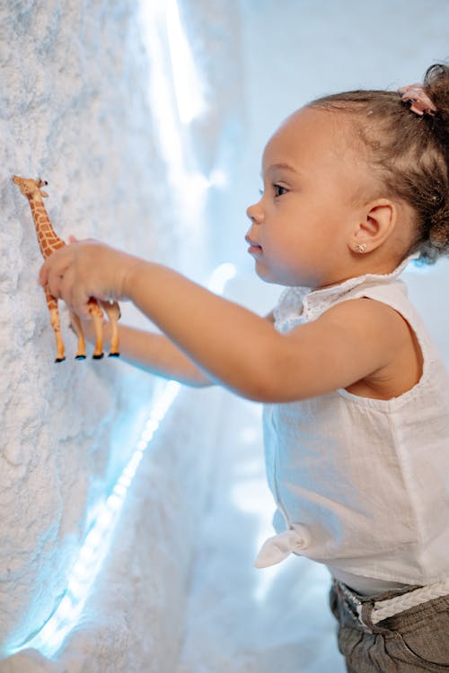 Girl in White Top Holding a Toy