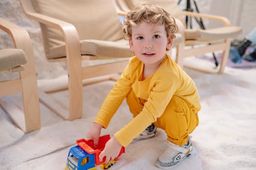 A Cute Boy Playing with His Toy while Looking at Camera