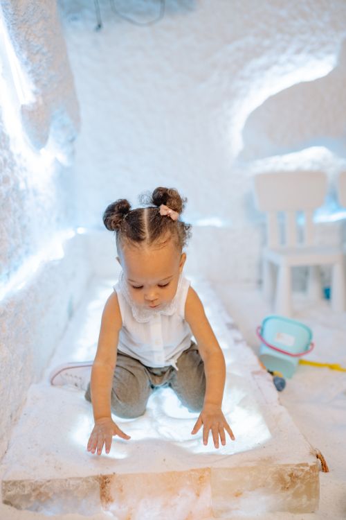 Free A cute toddler explores a salt room, engaging in sensory play indoors. Stock Photo