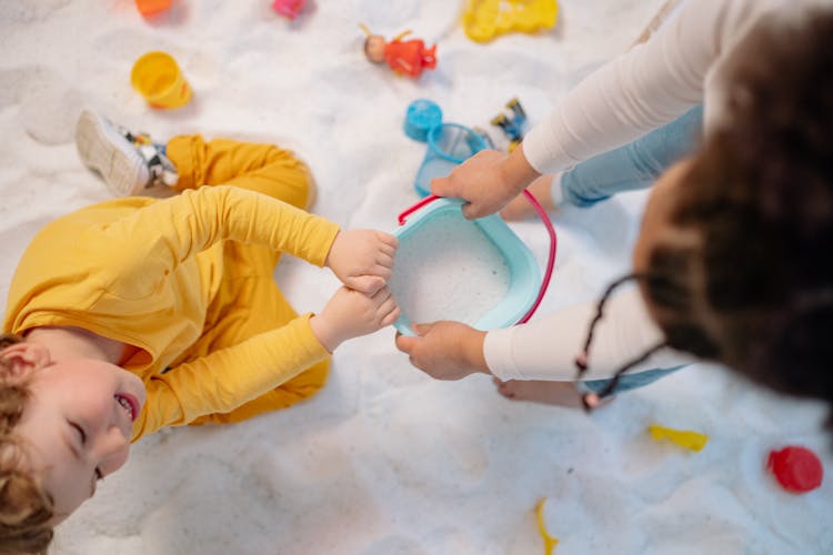 Children Playing With Sand In A Bucket