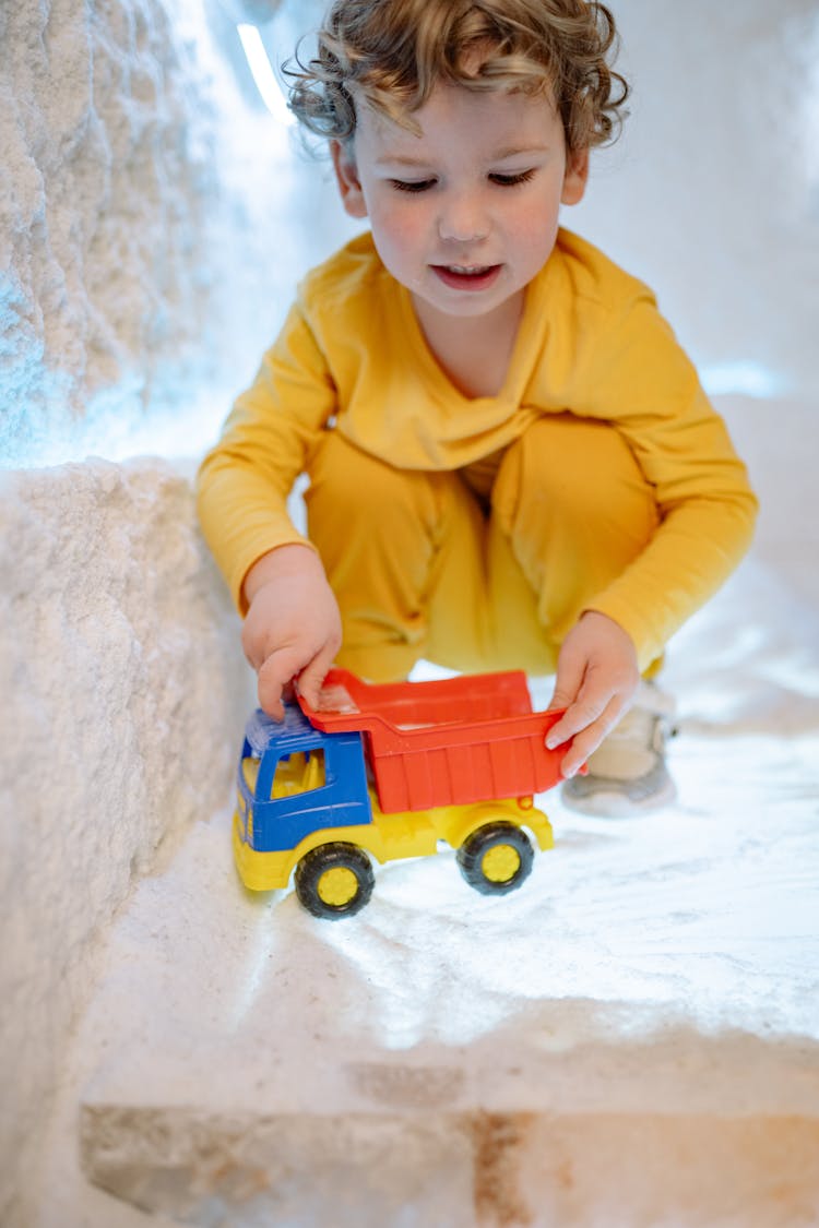 A Boy Playing With A Toy Truck