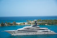 高端游艇沿着热带海岸线航行，海水清澈，绿树成荫