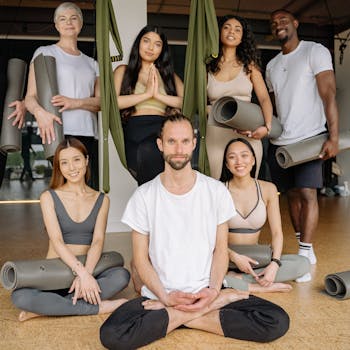 A diverse group of people in activewear enjoying a yoga class together with mats and smiles in a studio setting.