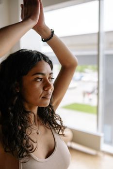 A young woman practicing yoga indoors with natural light.
