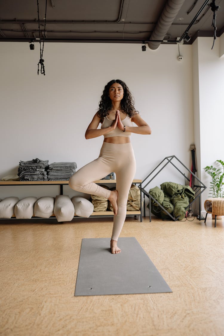 A Woman Doing Yoga While Standing On One Leg On A Yoga Mat