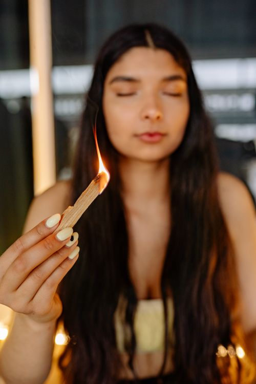 Free Close-up of a young woman meditating with a lit incense stick, eyes closed in relaxation. Stock Photo
