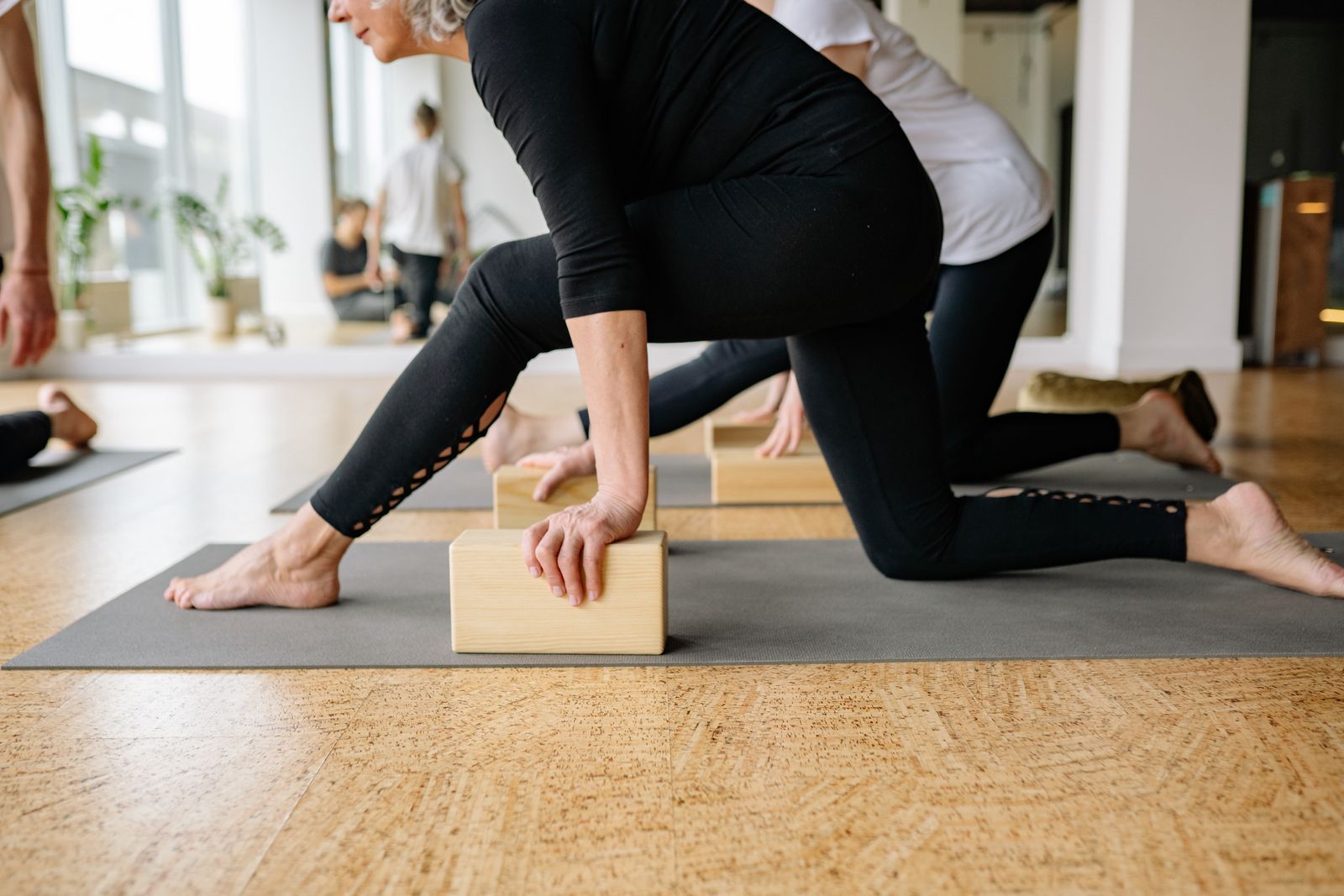 Adults practicing Iyengar yoga with wooden blocks in a bright studio