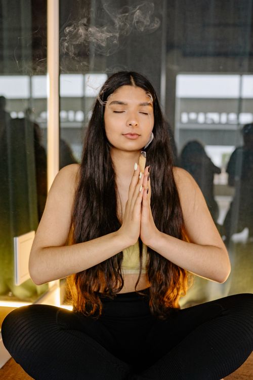 Free Peaceful woman meditating indoors with eyes closed, using Palo Santo for wellness. Stock Photo