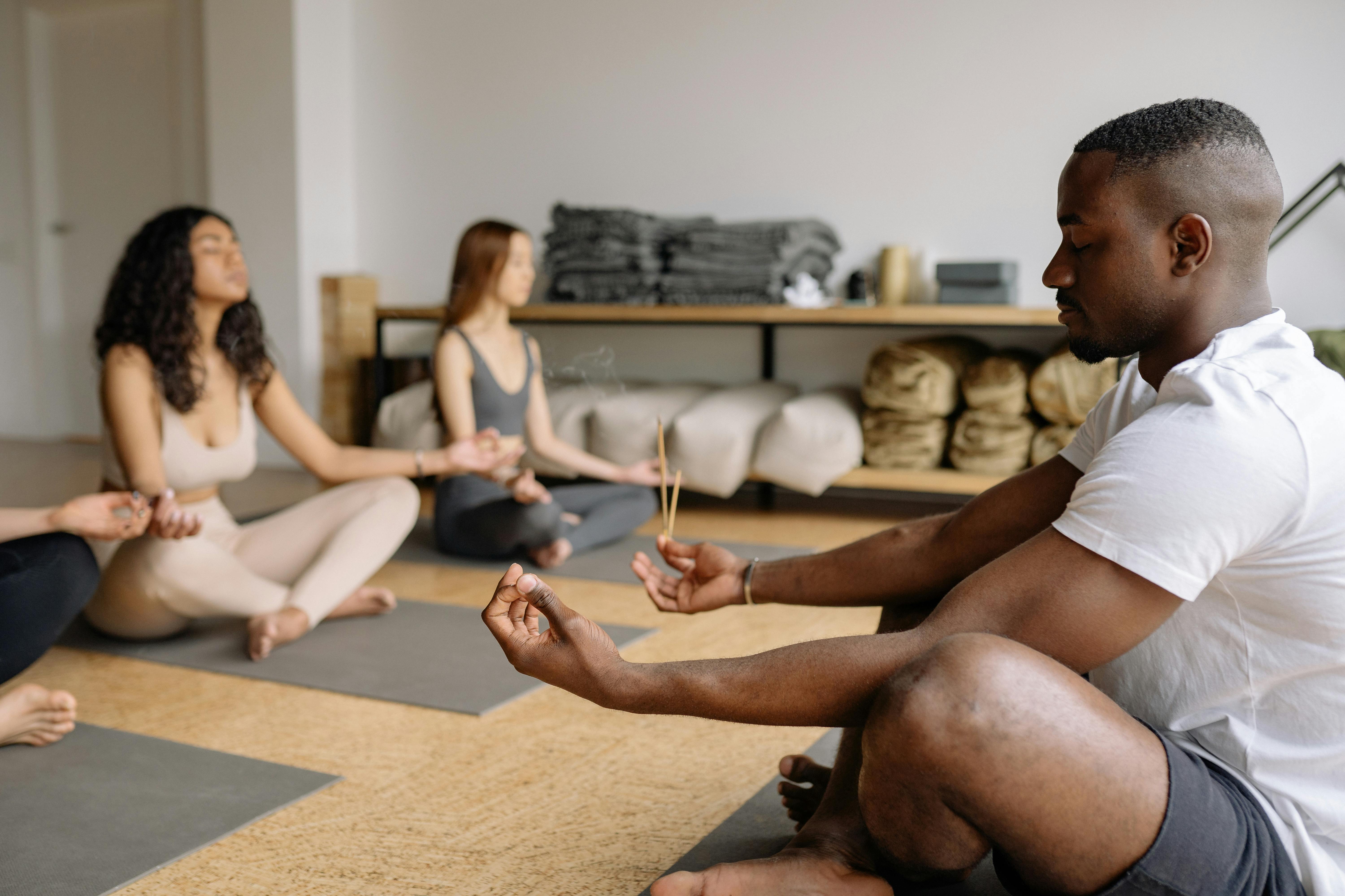 group health insurance Coral Springs companies - A diverse group practicing mindfulness meditation with incense in a serene indoor setting.