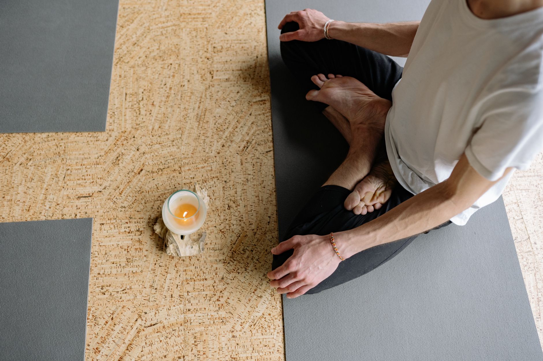 瑜伽情緒釋放技巧:釋放內在壓力,找回身心平靜 Adult meditating in lotus pose on yoga mat with candle, creating a calming atmosphere.
