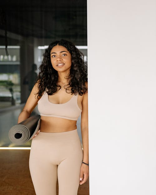 Woman in Beige Activewear Holding a Yoga Mat