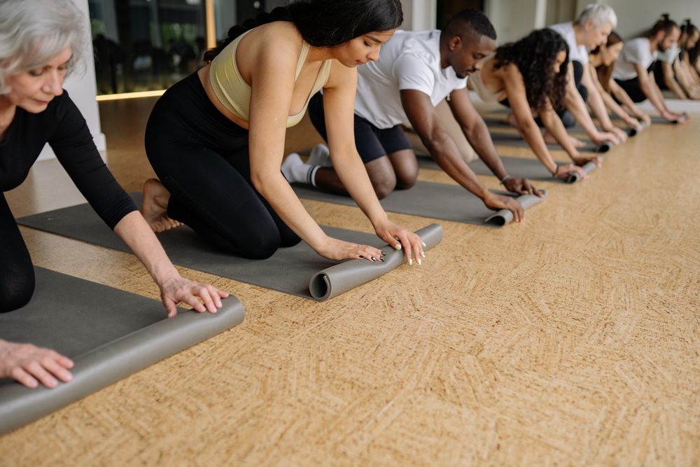 Students rolling yoga mats after class in a bright studio