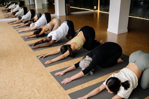 People Doing Stretching in Yoga Class