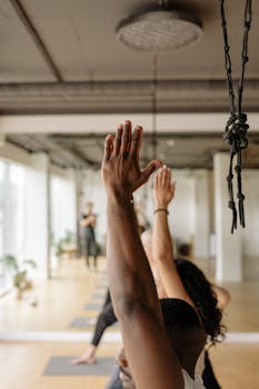 Yoga practitioners in an indoor studio, arms raised in a yoga pose, focusing on wellness.