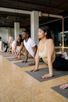 A diverse group of adults practicing yoga in an indoor studio, focusing on upward-facing dog pose for wellness and fitness.