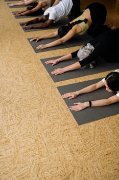 A group of people practicing stretching exercises on yoga mats in an indoor studio.