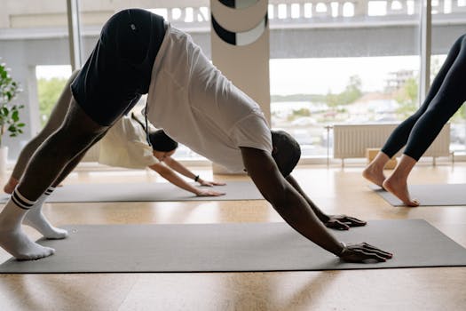 Diverse group of people performing yoga in a studio with bright natural light.