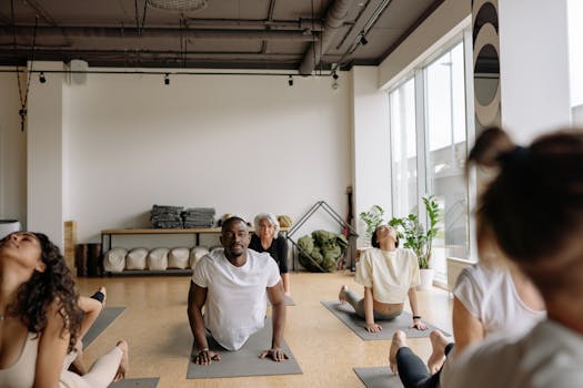 A group of diverse adults practicing yoga indoors on mats, focusing on stretching and mindfulness.