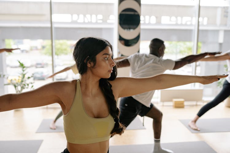 A Woman Doing The Warrior Pose In A Yoga Class