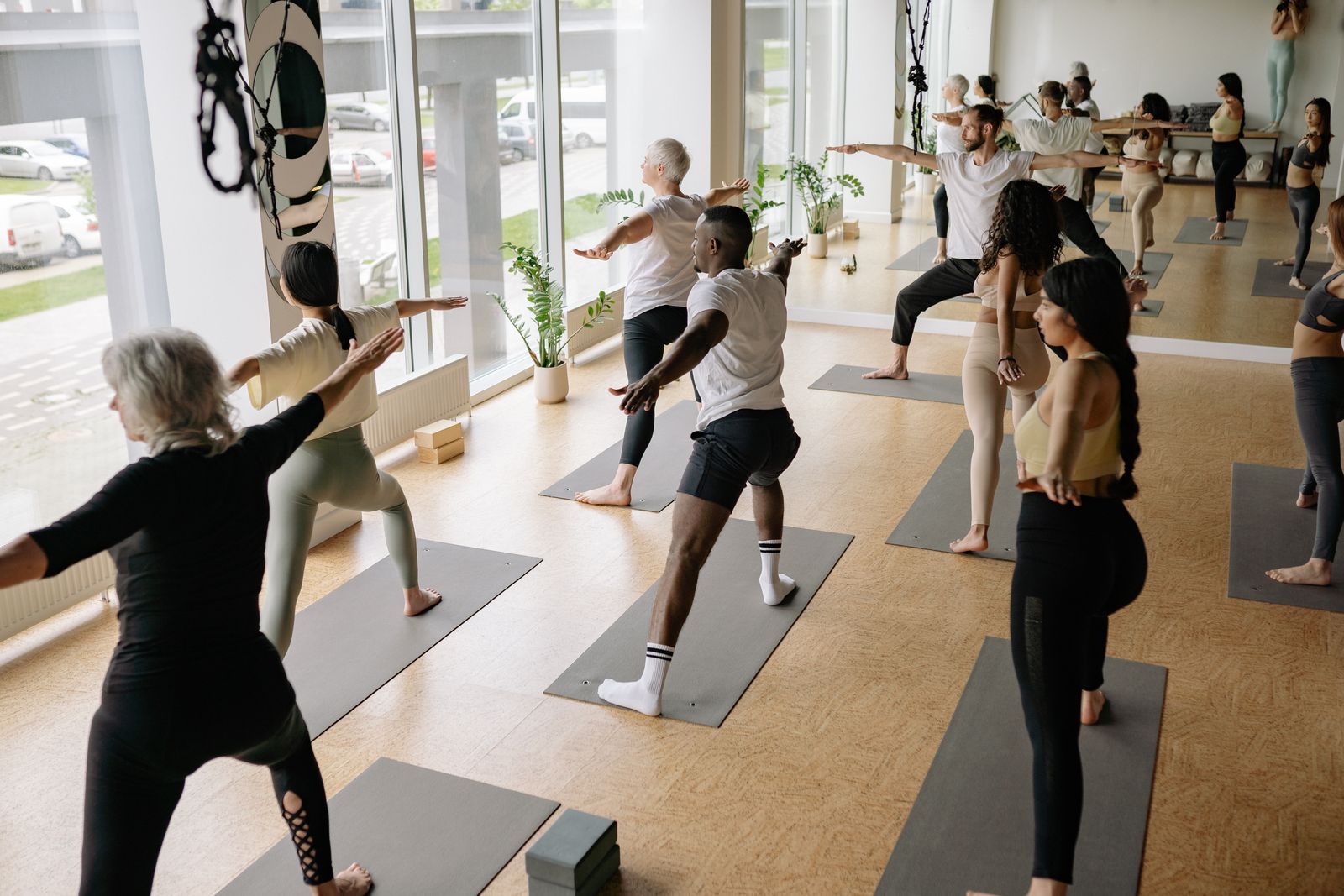 Group of yoga students flowing through warrior pose during a vinyasa yoga class in a bright studio