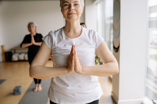 Elderly women in a yoga class practicing meditation and wellness indoors.