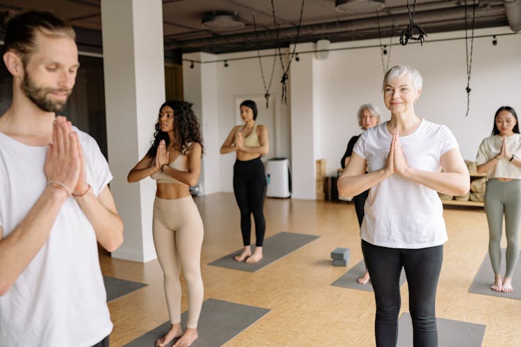 People In Yoga Class Doing A Namaste Mudra Hand Position
