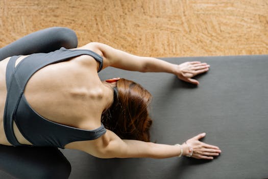 Top view of a woman in yoga pose on a mat with focus on posture and relaxation.