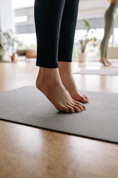 Close-up of a woman's bare feet on a yoga mat indoors, practicing balance.