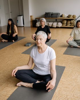 Senior woman and diverse group meditating in a yoga class for wellness and relaxation.